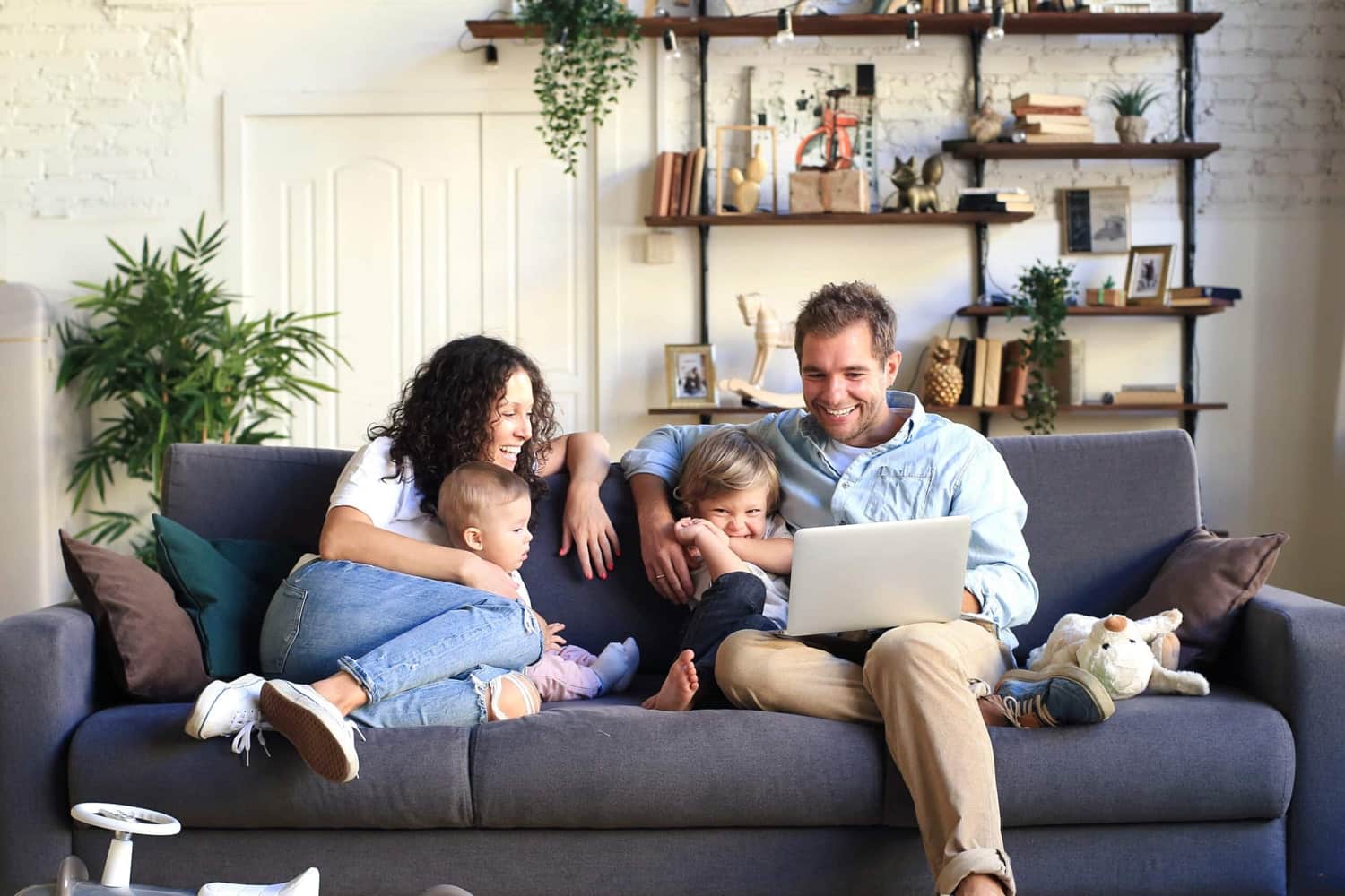 Young happy family on living room couch on a laptop enjoying the work done on their furnace.