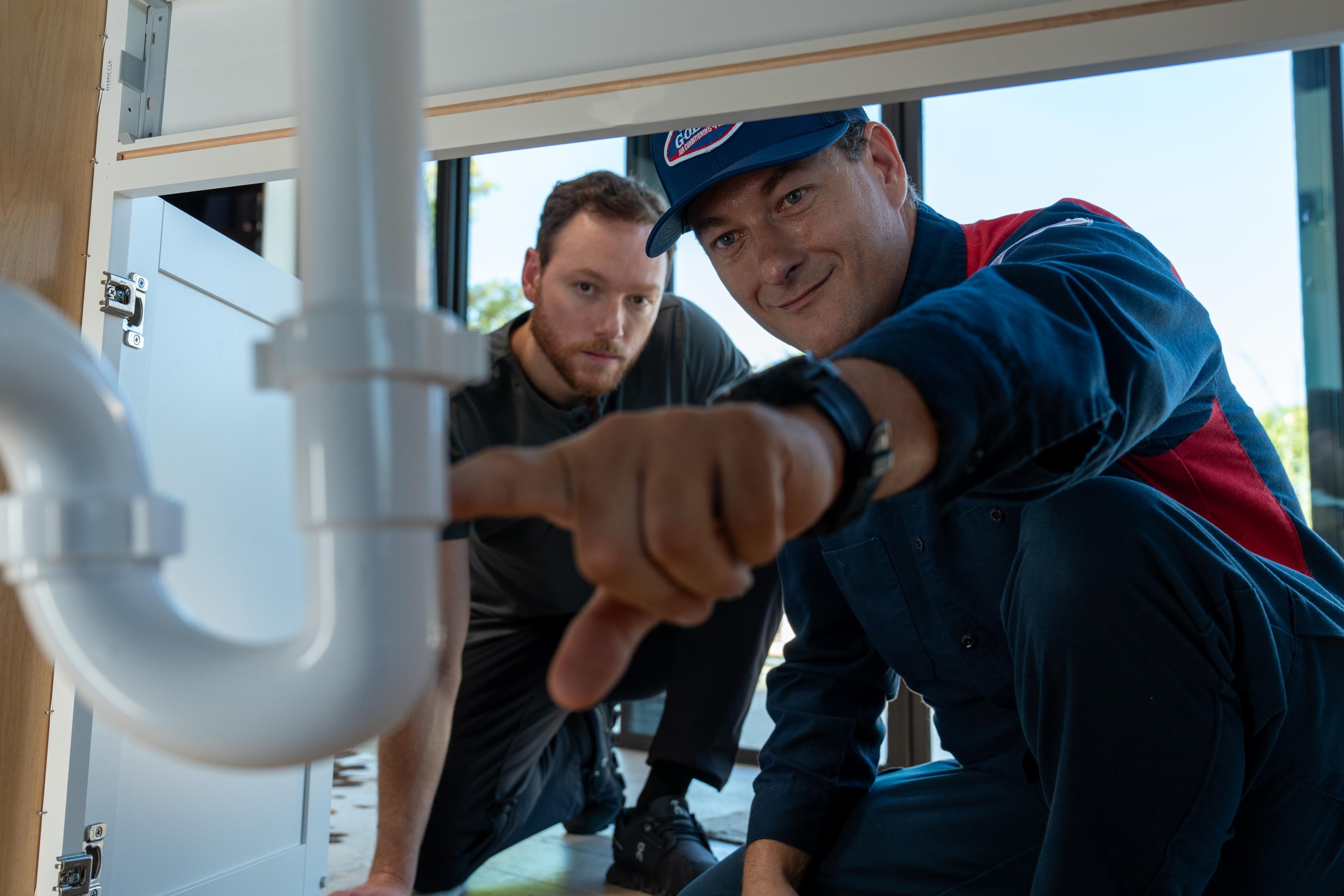 Goettl Plumber showing client the replaced pvc pipes under sink